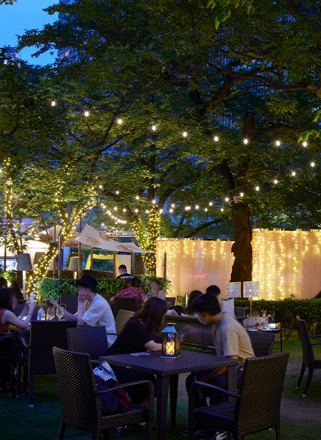 In an open lounge beneath shady trees.